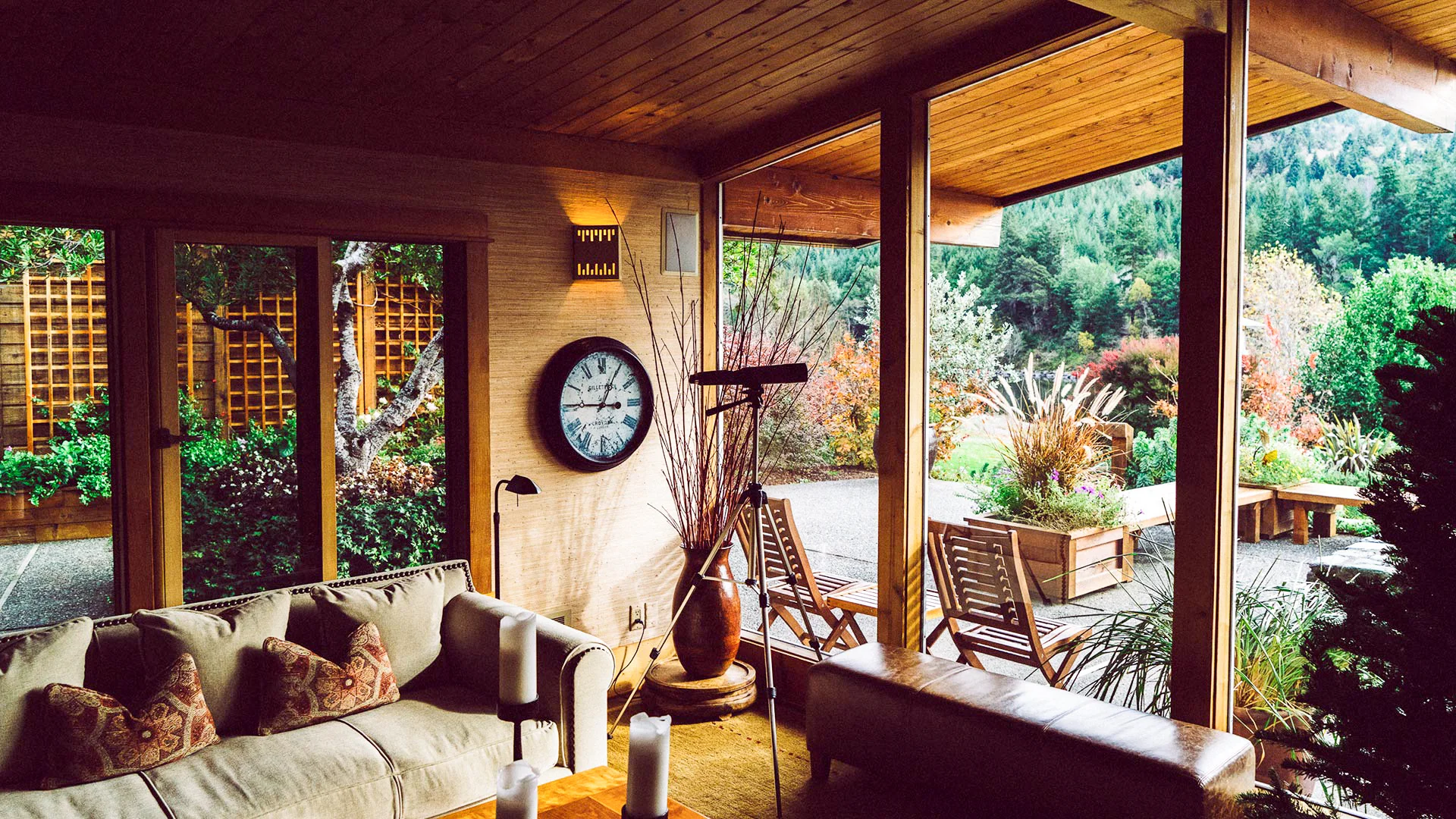 wood framed architectural glass wall and sliding doors looking out to patio and forest