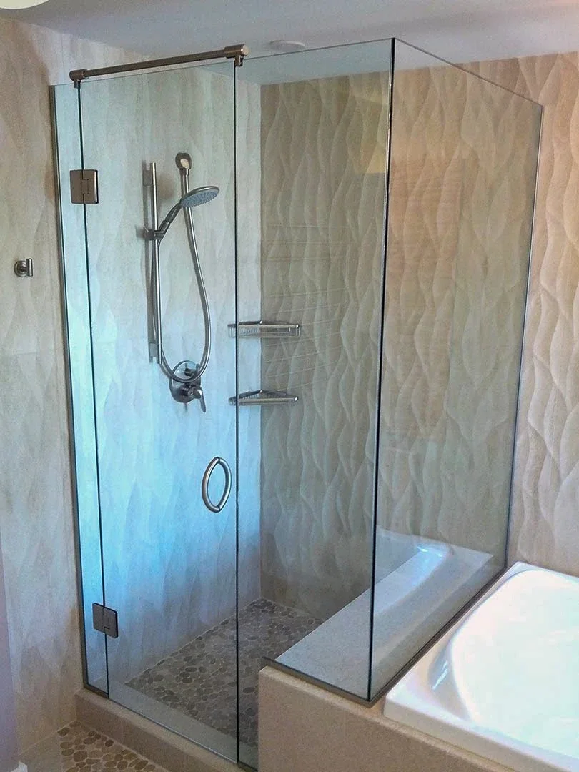 frameless glass shower enclosure with hinged door next to a bathtub