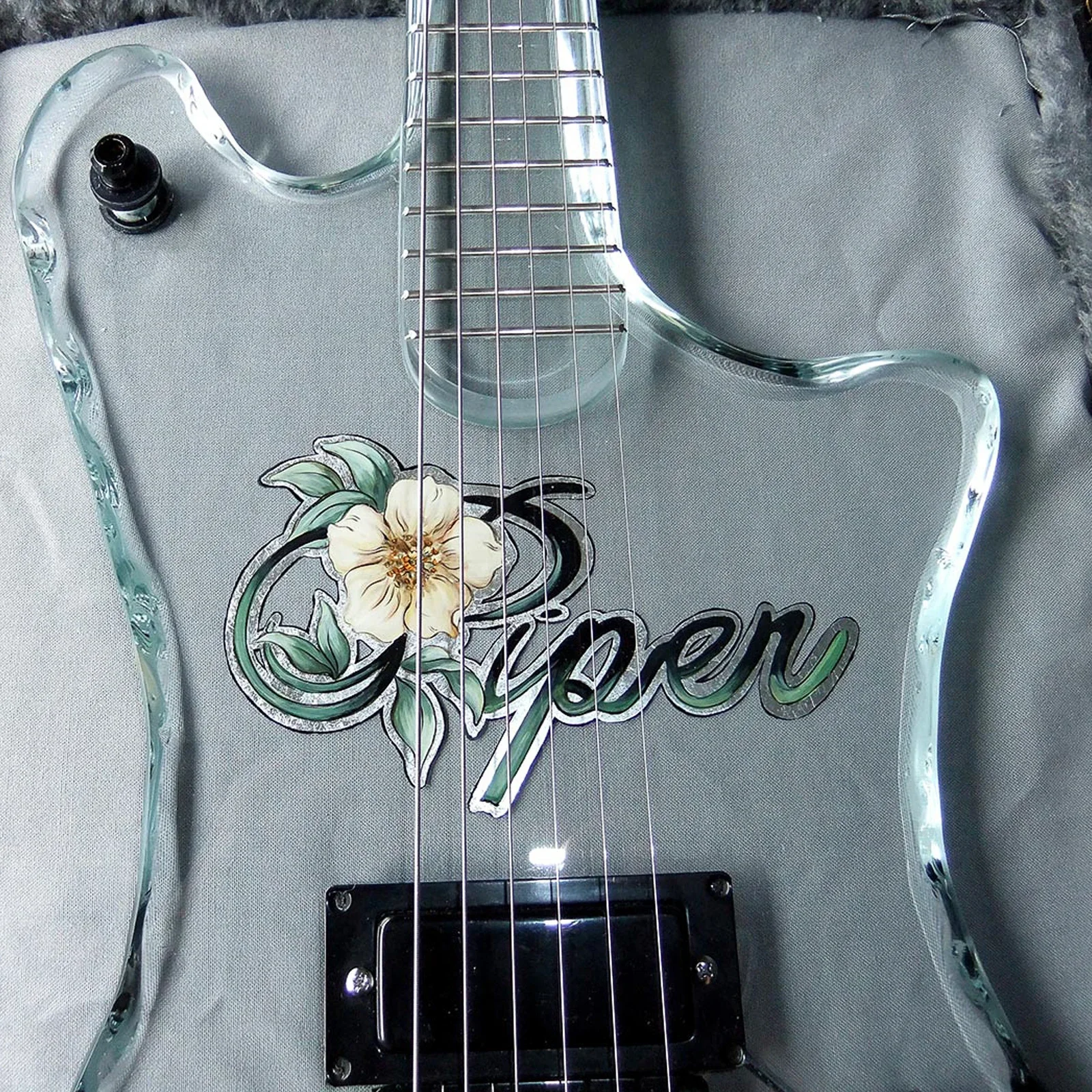 clear glass electric guitar body with floral painted piper logo under the strings